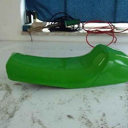 Ein grüner Motorradsitz steht auf einem weißen Boden